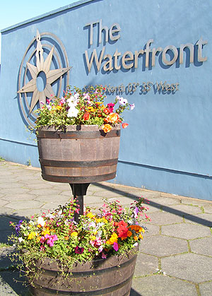 half barrel planters in front of Waterfront sign